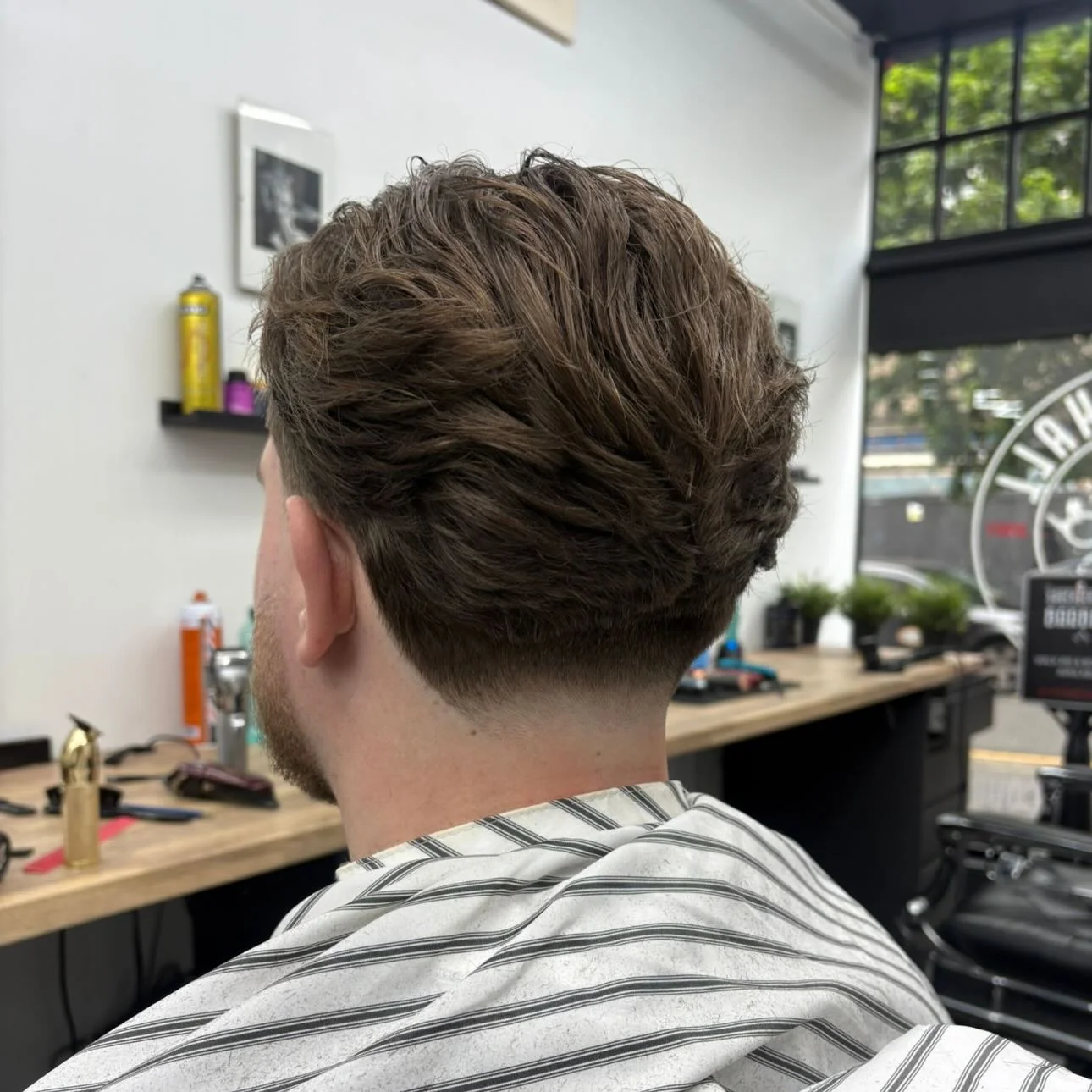 Textured wavy crop with a low taper, back view by the shop window