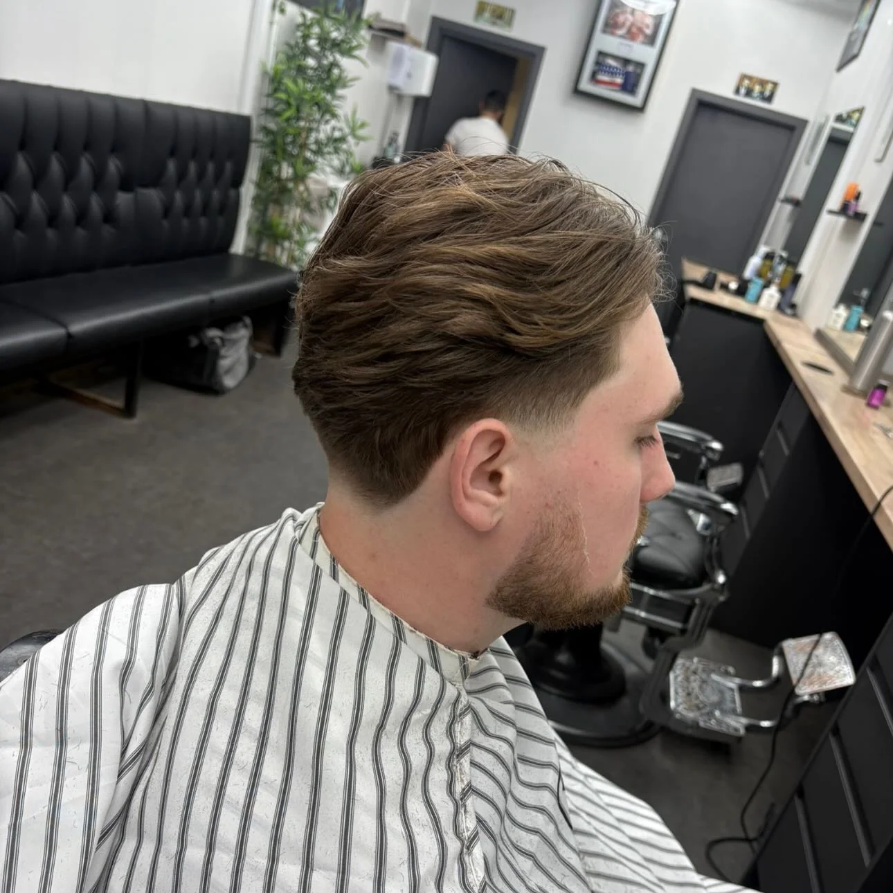 Textured crop with a low skin fade, side profile by the waiting area