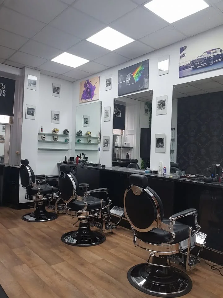 Inside Sauchiehall Barbers: chrome barber chairs, dark counters and glass shelves with skull decorations
